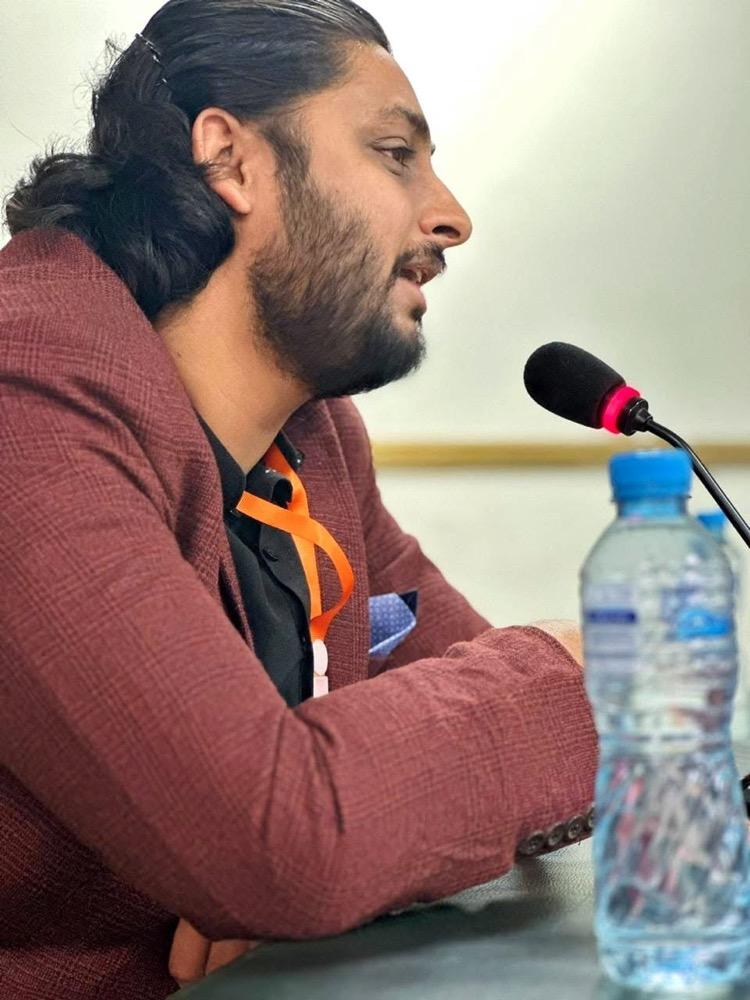 Alizaib Hassan speaking on a panel discussion into a microphone